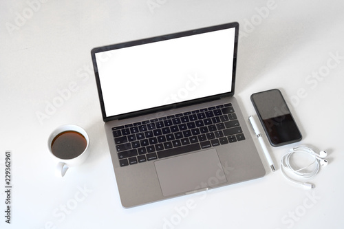 Mockup laptop with coffee mug on white desk.