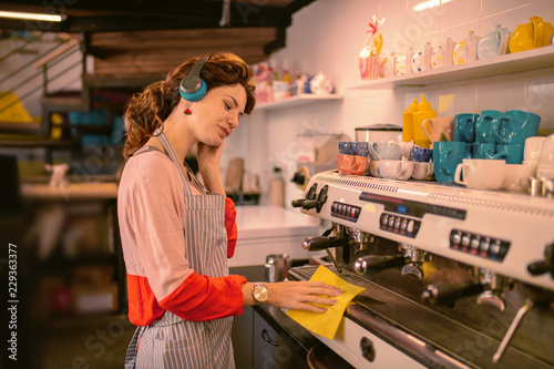 Try to relax. Kind girl listening to music while working in cafeteria