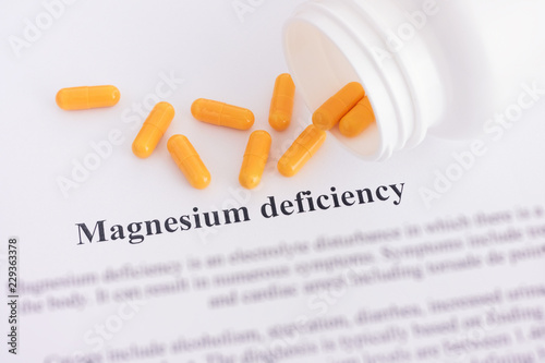 Magnesium deficiency diagnosis on paper with pills spilling out of a bottle