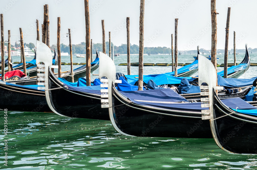Venice, Italy. Retro transport, details. Pier with old black wooden gondolas. The embankment of the Grand Canal in the autumn day. Venice, Italy. Retro transport, details. Pier with old black wooden gondolas. The embankment of the Grand Canal in the autumn day.