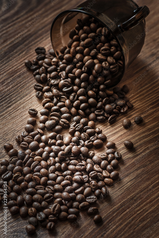 Coffee grains are scattered on a wooden table in the morning light in a rustic style.