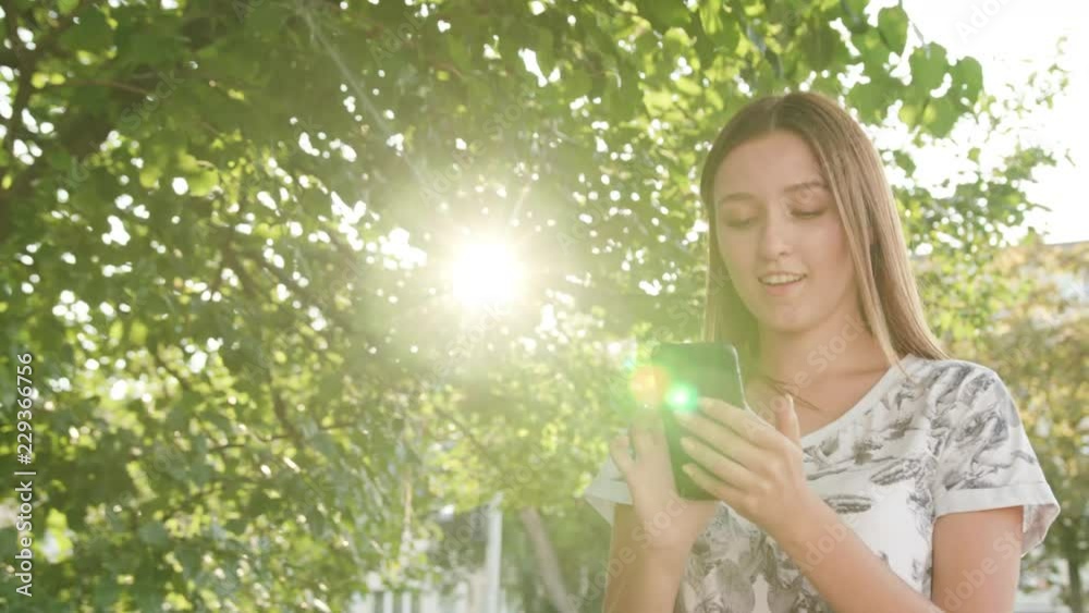 An attractive young lady using a phone in town while walking. Close-up dolly shot. Soft focus An attractive young lady using a phone in town while walking. Close-up dolly shot. Soft focus