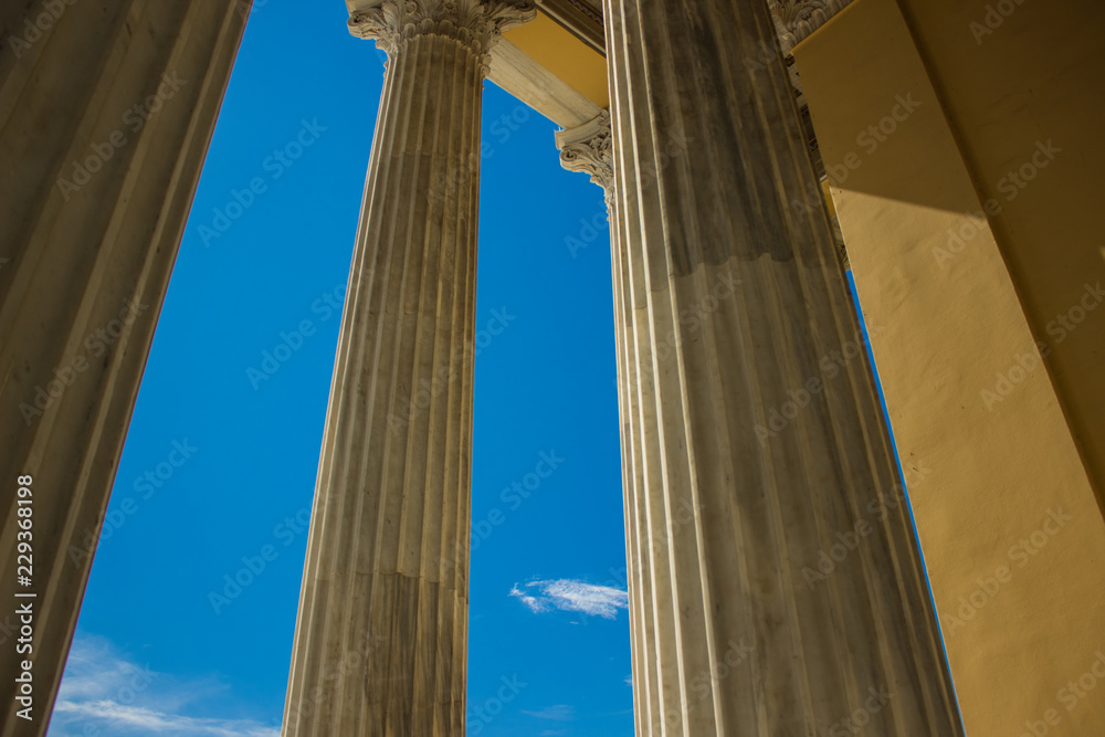 architecture building concept of ancient Greek temple with yellow marble columns on blue sky background