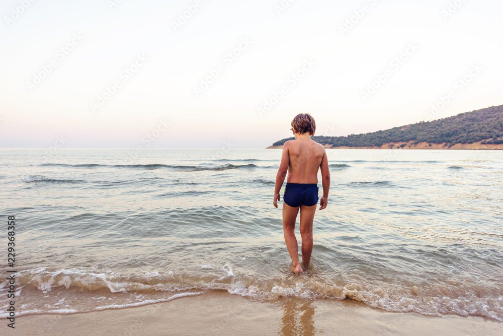 Fototapeta premium Child entering water at sunset