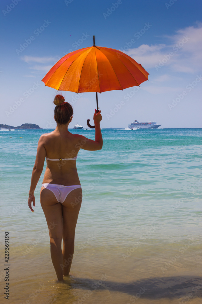 girl with orange umbrella on the beach in Thailand girl with orange umbrella on the beach in Thailand