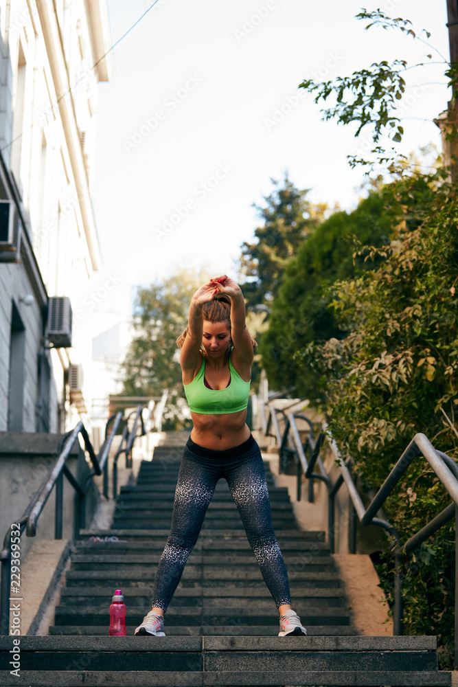 Portrait of  sporty young woman doing stretching in city.
