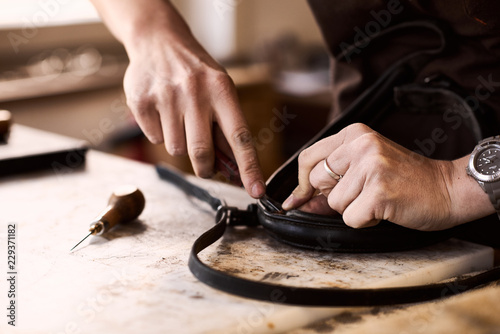 Canvastavla Hände einer Handwerkerin beim Leder-Verarbeiten in Brauntönen und Werkzeug