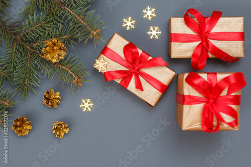 Gift boxes, fir tree branches with cones on gray background