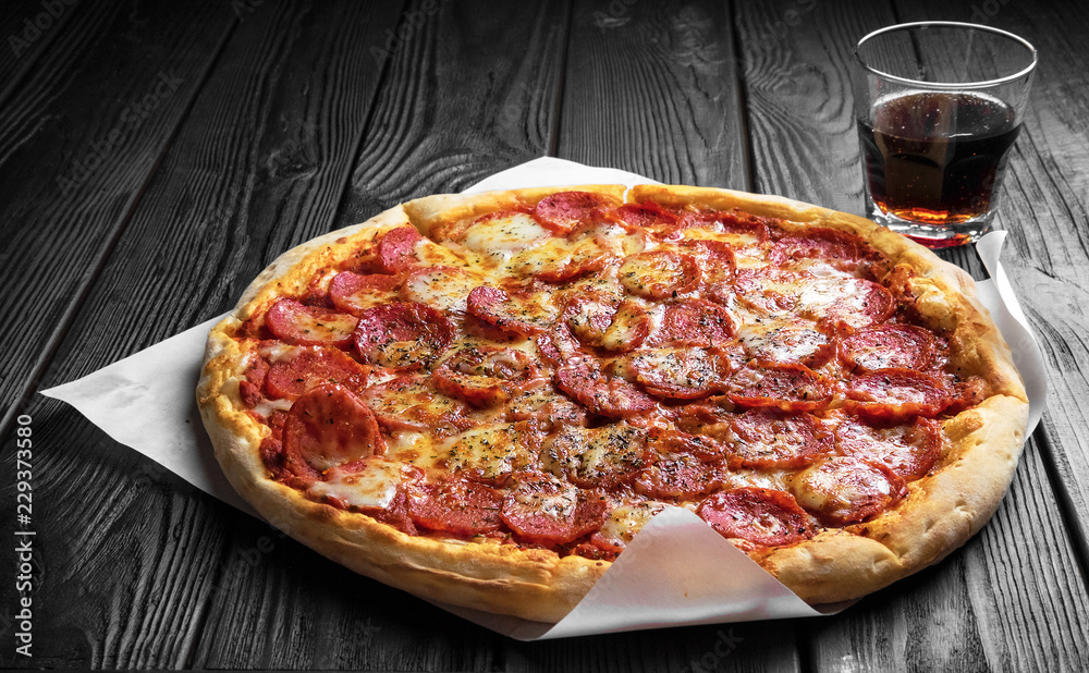 pepperoni pizza on dark black wooden board, traditional italian pizza, glass of cola