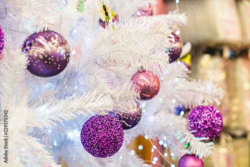 Trendy purple  ultraviolet colored baubles on silver white artificial Christmas tree. Close up. Selective focus  copy space.