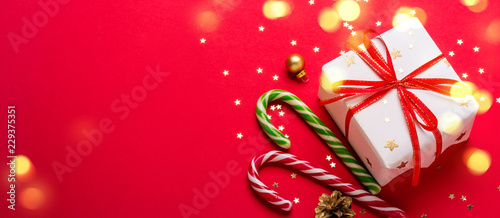 Christmas gift box and candy cane with shining lights. Long banner format