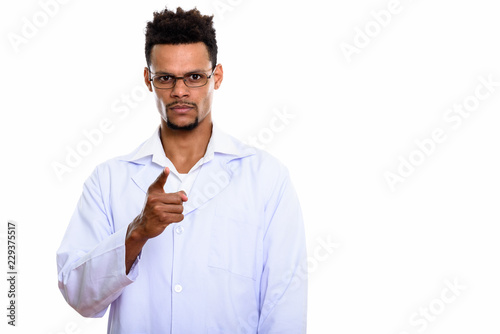 Studio shot of young African man doctor pointing at camera