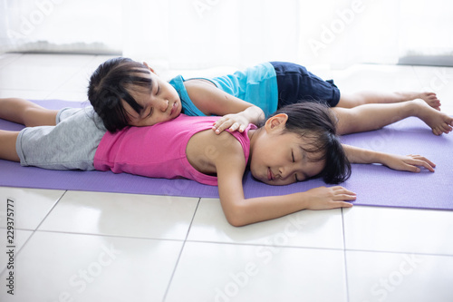 Asian Chinese little sisters lying on yoga mat