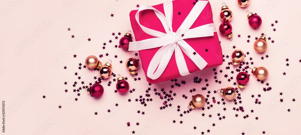 Fototapeta premium Christmas gift and balls with confetti on pastel background. Long banner format