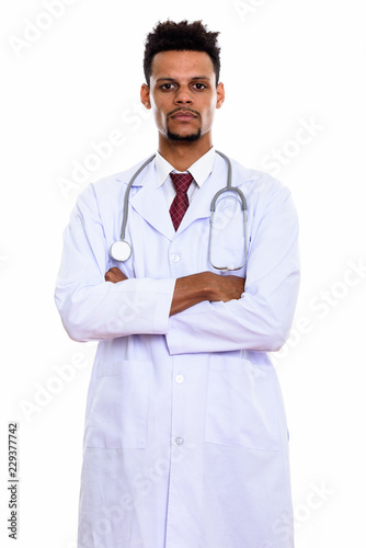 Studio shot of young African man doctor standing with arms cross