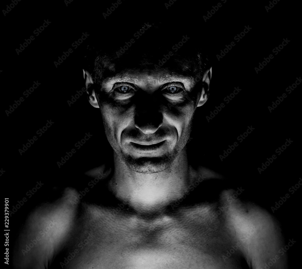 Stylish dark portrait of caucasian who looks straight at you looks like maniac. Expressive Black and white shot, low key lighting. Stock Photo | Adobe Stock