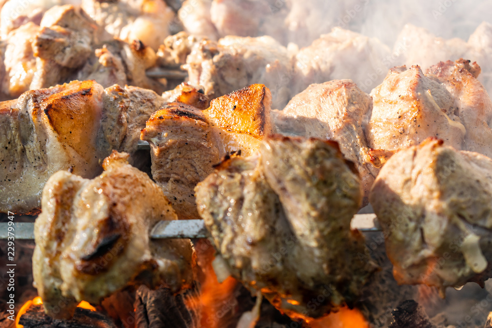 Grilled meat, Golden pork with skewers and wooden handles. A lot of smoke in the process of cooking fragrant meat dishes in nature. Summer kitchen. Raw meat on fire. Grilled meat, Golden pork with skewers and wooden handles. A lot of smoke in the process of cooking fragrant meat dishes in nature. Summer kitchen. Raw meat on fire.