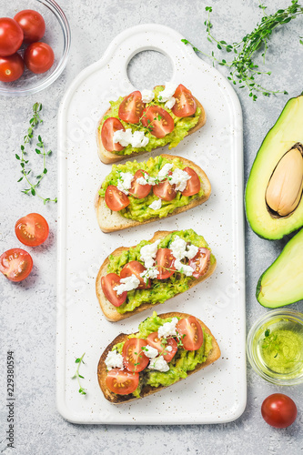 Avocado cherry tomatoes feta cheese toasts on board. Top view, space for text.