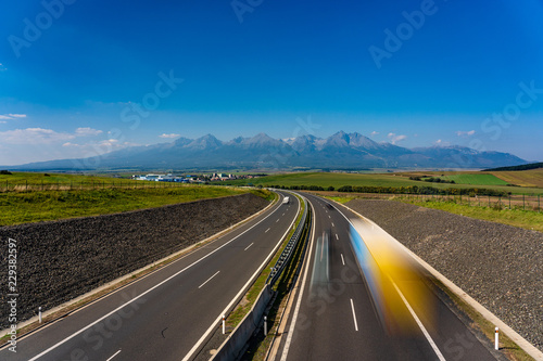 Scenic view of highway leading to rocky peaks of High Tatras mountains, Slovakia summer day.
