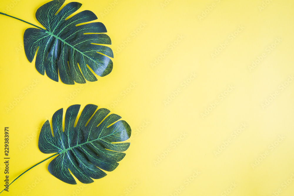 Flat lay of palm leaves against yellow background. Minimal nature summer concept.