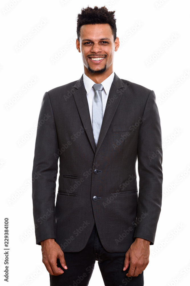 Studio shot of young happy African businessman smiling while st Studio shot of young happy African businessman smiling while st