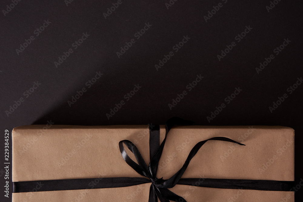 top view of craft wrapped gift box on black surface, black friday concept