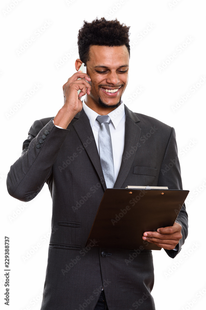 Young happy African businessman smiling while reading on clipboa Young happy African businessman smiling while reading on clipboa