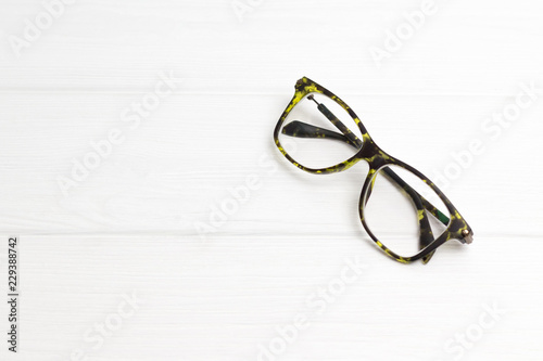 Modern black-green glasses on white wooden background. Minimalism. Front view