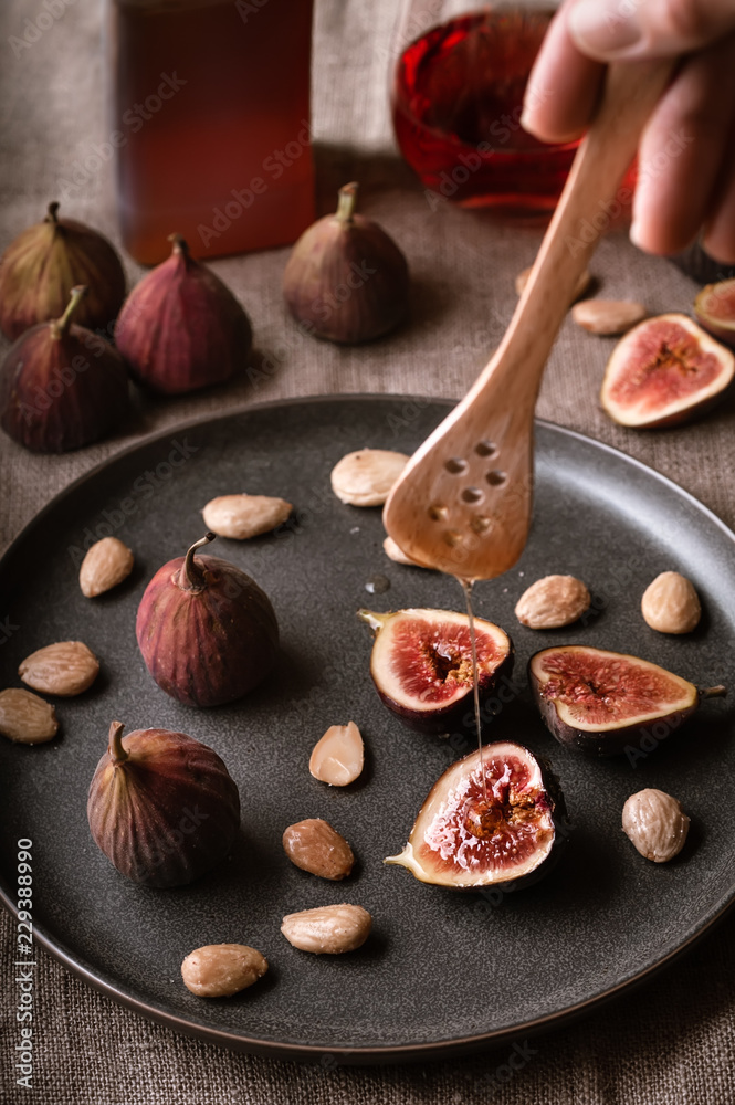 Drizzling honey on a plate of figs and marcona almonds.