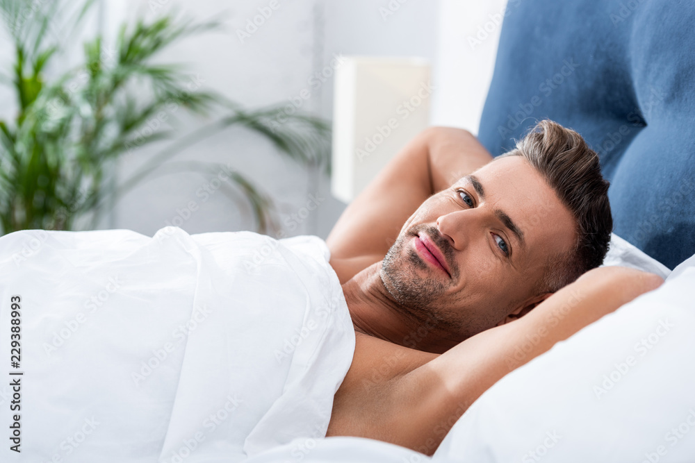 selective focus of happy adult man laying in bed at home selective focus of happy adult man laying in bed at home