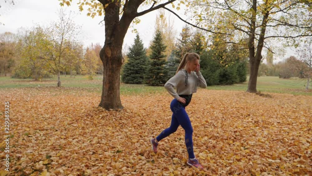 Young blonde female doing sports morning fitness workout in autumn park slow motion Young blonde female doing sports morning fitness workout in autumn park slow motion