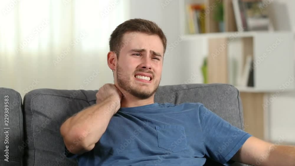 Man suffering neck ache sitting on a couch at home Man suffering neck ache sitting on a couch at home