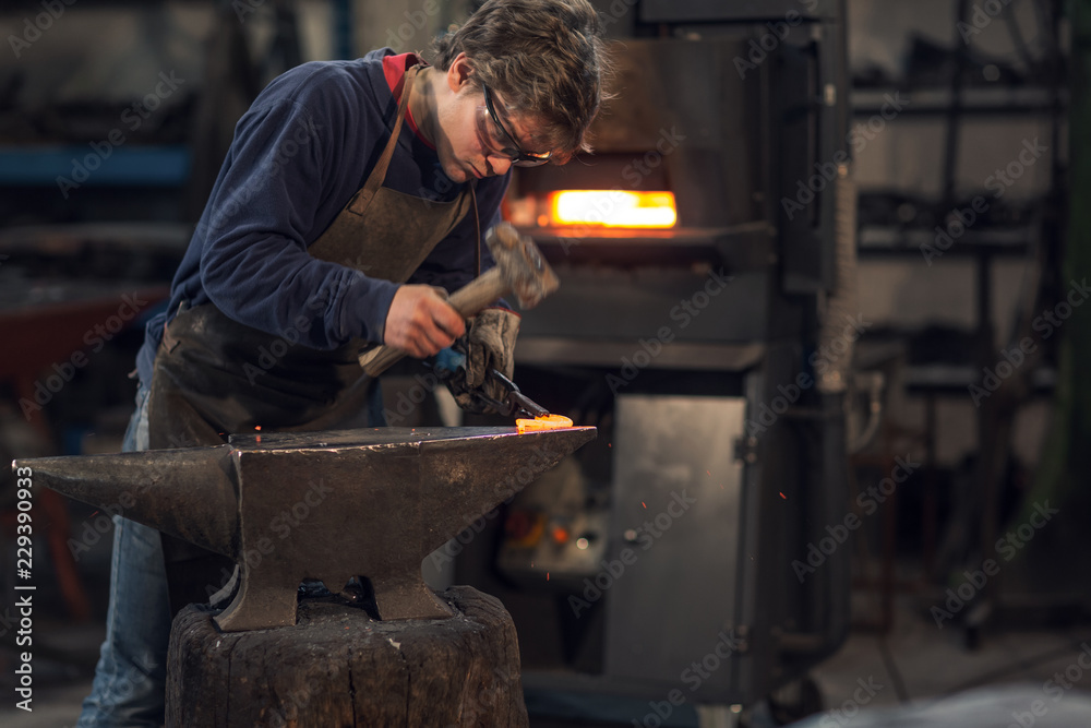 Young blacksmith working with red hot metal Young blacksmith working with red hot metal