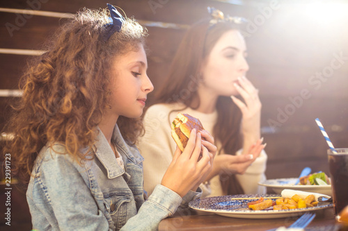 Mother and daughter eating burgers