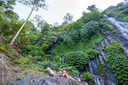 Young woman in pink swimsuit sitting on the rock photo