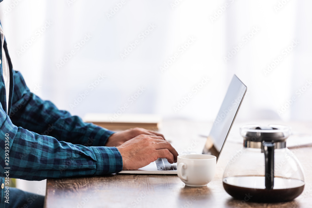 close-up partial view of man in checkered shirt using laptop at home close-up partial view of man in checkered shirt using laptop at home