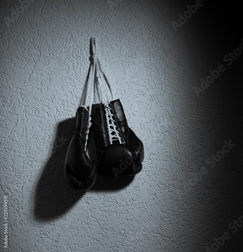 A Pair of Black Boxing Gloves Hang on Nail on a Wall