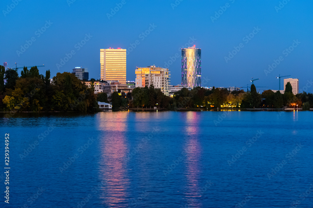City lights reflecting at night over the water of Herastrau lake in Bucharest Romania City lights reflecting at night over the water of Herastrau lake in Bucharest Romania