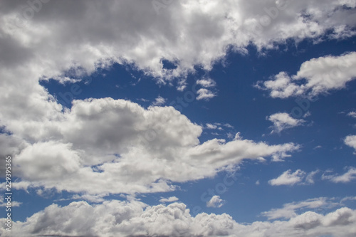 Blue sky with white clouds tinged with grey  - cumulus