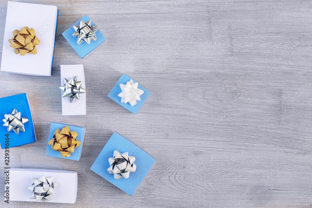 Copy space on a light wooden background. White and blue gift boxes with beautiful bows. Festive Christmas composition.