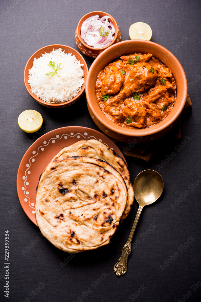 Murgh Makhani / Butter chicken tikka masala served with roti / Paratha and plain rice along with onion salad. selective focus