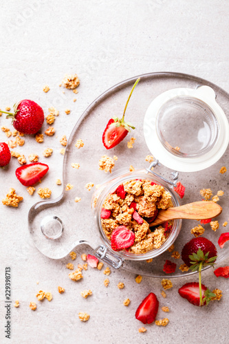 Granola Cereal bar with Strawberries on the Gray Background in a glass jar. Muesli Breakfast. Healthy Food sweet dessert snack. Diet Nutrition Concept. Top View. Vegetarian food.Flat Lay.Copy space