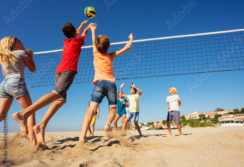 Beach volleyball players jumping to spike the ball