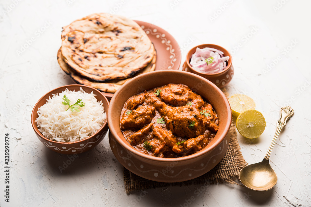 Murgh Makhani / Butter chicken tikka masala served with roti / Paratha and plain rice along with onion salad. selective focus Murgh Makhani / Butter chicken tikka masala served with roti / Paratha and plain rice along with onion salad. selective focus