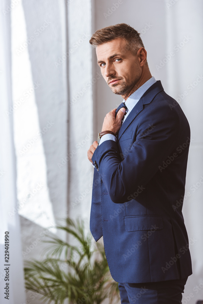 handsome man in suit wearing necktie and looking at camera handsome man in suit wearing necktie and looking at camera