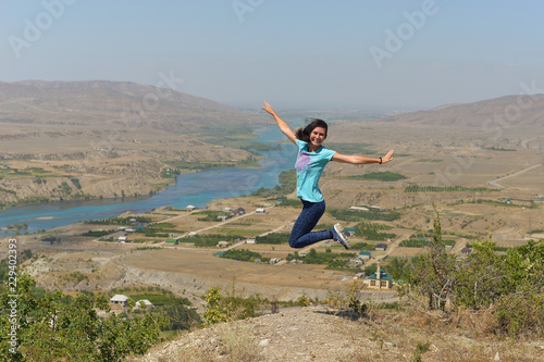 Sulak river in Dagestan and the village along the river. Woman jumping with happiness and joy.
