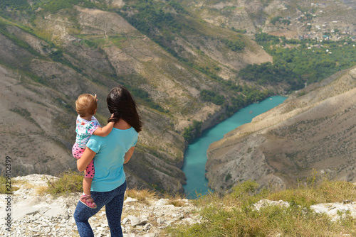 Sulak canyon in Dagestan, one of the deepest in the world. A woman with a child in her arms enjoys the view of the canyon and the turquoise river Sulak.