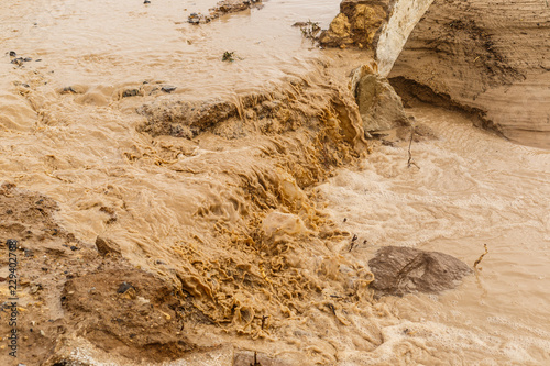 Strong storm erode the farmland, dragging the fertile surface and causing muddy floods. Detail of brown water of stream after natural disaster