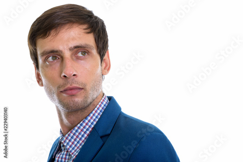 Studio shot of young handsome businessman thinking while looking