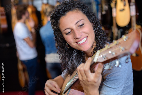 cheerful smiling teenage girl posing with classical guitar in shop
